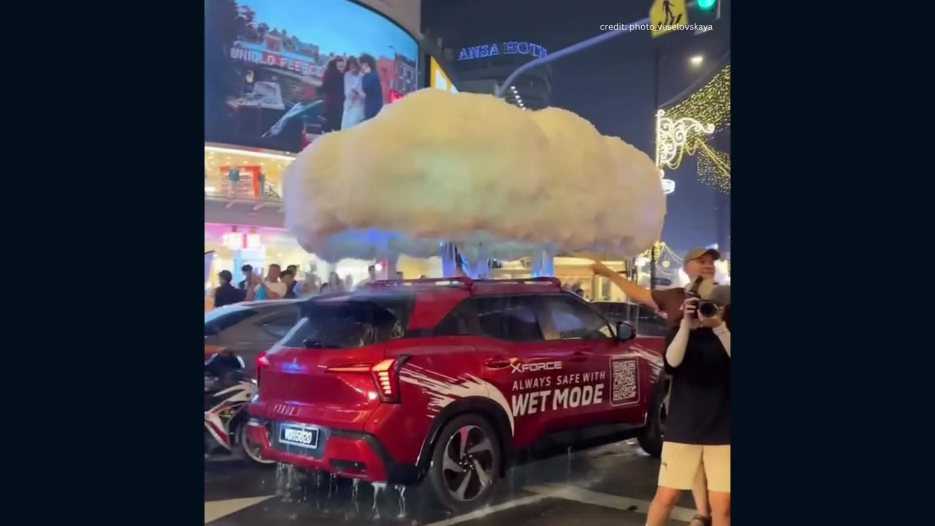 La nube artificial deja caer agua sobre el Mitsubishi Xforce en una calle nocturna.