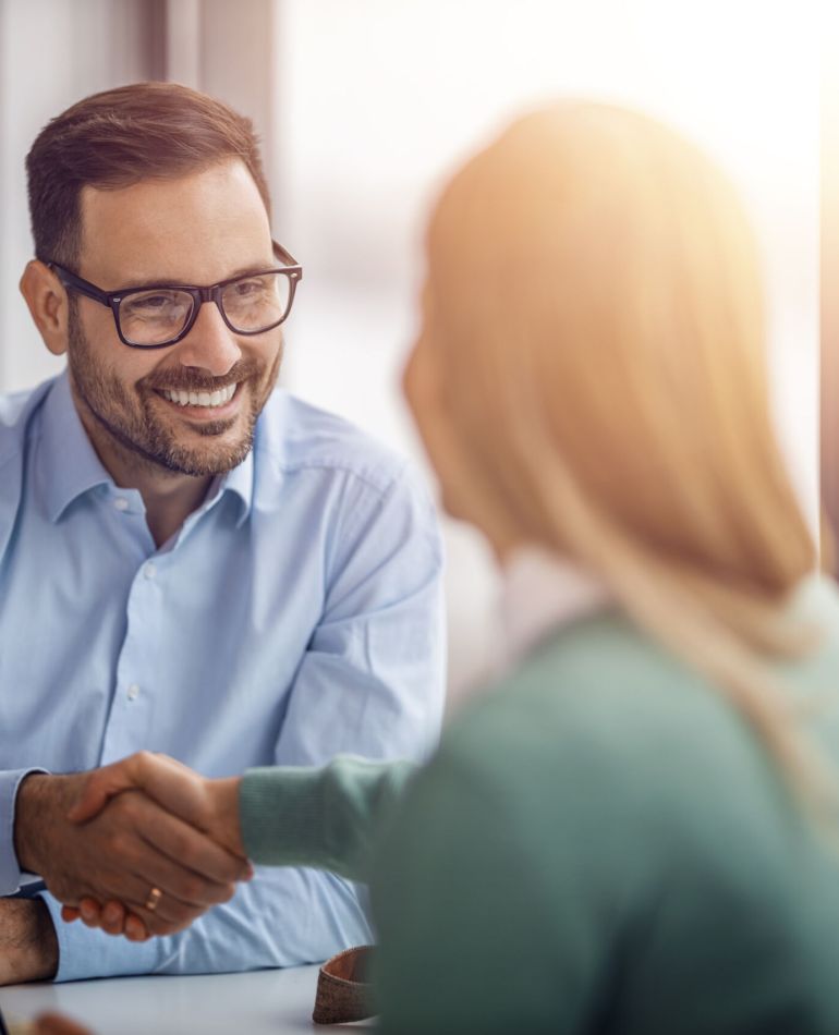 Young businessman shaking hands and smiling while working in modern office.Job interview.